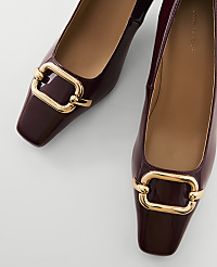 A pair of glossy burgundy square-toe flats with gold buckle details are laid out on a plain white background. carousel Product Image 2