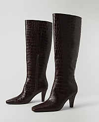 A pair of dark brown, croc-embossed leather knee-high boots with pointed toes and stiletto heels stand on a plain white surface against a white background. carousel Product Image 2