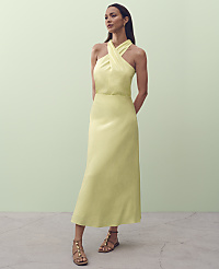 A woman in a pale yellow halter dress stands on a concrete floor against a pale green wall. carousel Product Image 4