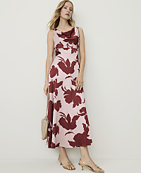 A woman in a floral dress and heels stands against a plain background, holding a small purse. carousel Product Image 1