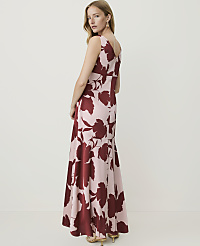 A woman in a floral maxi dress stands against a plain, light-colored background. carousel Product Image 2