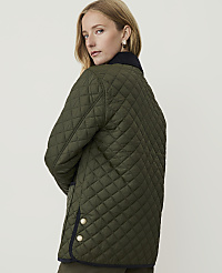 A woman in a quilted green jacket with a dark collar and gold buttons stands against a plain, light background. carousel Product Image 2