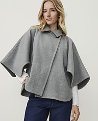 A blonde woman in a grey cape and blue jeans stands against a plain white background. carousel Product Image 1