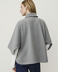 A woman in a grey poncho and white sweater stands against a plain grey background. carousel Product Image 2