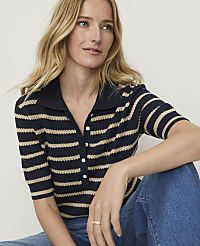 A woman with blonde hair wears a striped polo shirt and blue jeans, with a plain background. carousel Product Image 1