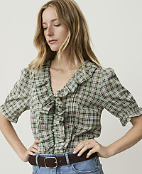 A woman in a ruffled plaid blouse and jeans stands against a plain background. carousel Product Image 1