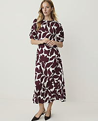 A woman in a floral dress stands against a plain white background. carousel Product Image 1