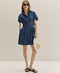 A woman in a denim dress and sunglasses stands with a hat in her hand against a plain, light-colored background. carousel Product Image 3