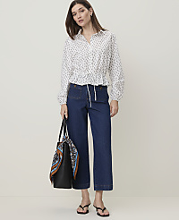 A woman in a patterned blouse and dark jeans stands with a tote bag in front of a plain white background. carousel Product Image 1