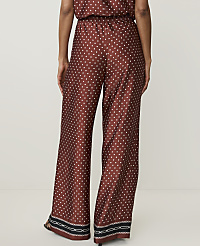 A person wearing patterned wide-leg pants stands against a plain white background. carousel Product Image 3