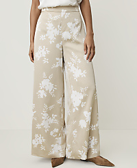 A person stands wearing wide-leg beige pants with a white floral pattern, against a plain white background. carousel Product Image 2