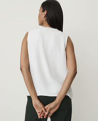 A woman in a white sleeveless top and dark green pants stands with her back to the camera against a plain white background. carousel Product Image 2