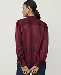 A woman in a burgundy striped blouse stands with her back to the viewer against a plain, light-colored background. carousel Product Image 2