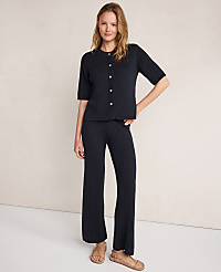 A woman in a dark ribbed knit cardigan and matching pants stands against a plain, light-colored background. carousel Product Image 2