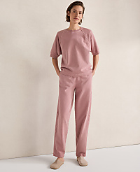 A woman in a pink loungewear set stands with her hands in her pockets against a plain, light-colored wall. carousel Product Image 3