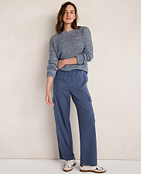 A woman in a blue sweater and blue cargo pants stands against a textured off-white wall. carousel Product Image 3