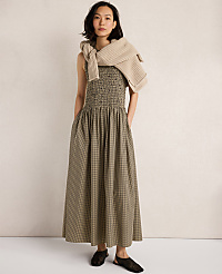A woman in a green smocked dress and a beige sweater draped over her shoulders stands against a plain, light-colored background. carousel Product Image 5
