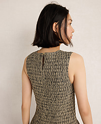 A woman with short dark hair, seen from the back, wears a textured sleeveless dress against a plain, light-colored background. carousel Product Image 2