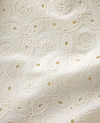 Intricate white eyelet embroidery forms a repeating geometric pattern against a soft, textured fabric background. carousel Product Image 4