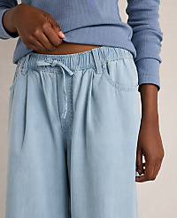 A person's hands adjust the drawstring waist of light blue, wide-leg pants against a plain background. carousel Product Image 3