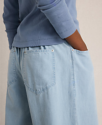 A person in a blue long-sleeved shirt has their hands in the pockets of light blue wide-leg pants against a plain background. carousel Product Image 2