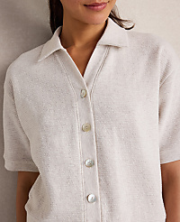 A woman in a textured cream collared shirt with pearl buttons is shown against a neutral, textured background. carousel Product Image 3