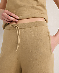 A person's midsection is shown in the foreground, wearing tan loungewear with a drawstring waist, against a plain, light-colored background. carousel Product Image 2