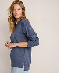 A blonde woman in a blue sweatshirt stands against a plain, light-colored background. carousel Product Image 3