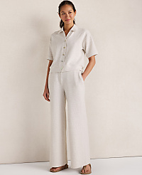A woman in a linen shirt and wide-leg pants stands against a textured, light-colored wall. carousel Product Image 3