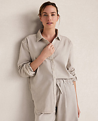 A woman in a light-colored button-down shirt and pants stands against a textured, neutral wall. carousel Product Image 1