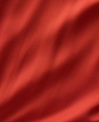 A close-up of rippling red fabric fills the frame, with soft shadows creating depth and texture. carousel Product Image 4