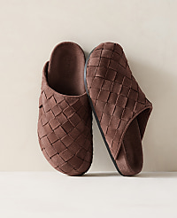 A pair of brown woven slippers rests on a light-colored surface against a soft, neutral background. carousel Product Image 1