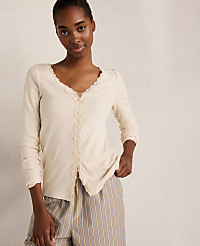 A woman in a cream-colored lace-trimmed top and striped pants stands against a plain, light-colored background. carousel Product Image 1