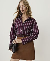 A woman in a striped shirt and brown skirt holds a clutch in front of a plain background. carousel Product Image 1