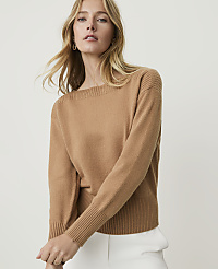 A woman in a tan sweater and white pants stands against a plain white background. carousel Product Image 1