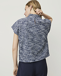 A woman in a textured blue top and dark pants stands against a plain, light background. carousel Product Image 2