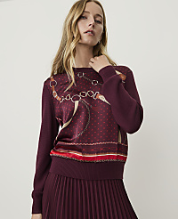 A woman in a burgundy sweater with a patterned front stands against a plain background. carousel Product Image 1