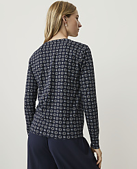 A woman in a patterned shirt and dark pants stands against a plain, light background. carousel Product Image 2