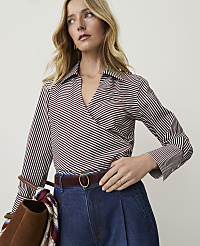 A woman in a striped wrap top and denim jeans stands against a plain background, holding a brown bag. carousel Product Image 1