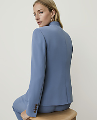 A woman in a blue blazer and pants sits against a plain, light-colored background. carousel Product Image 2