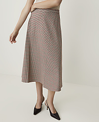 A woman models a plaid midi skirt and black slingback heels against a plain white background. carousel Product Image 2