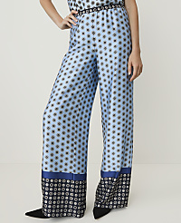A person stands in wide-leg, light blue patterned pants with a dark blue and black geometric border at the hem, against a plain white background. carousel Product Image 2