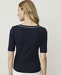 A woman in a navy blue top with a scalloped neckline stands against a plain white background. carousel Product Image 2