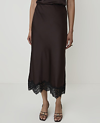 A person stands in front of a plain white background, wearing a brown satin skirt with a black lace trim and strappy sandals. carousel Product Image 2
