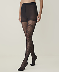 A person stands wearing black lace-patterned tights against a plain, light-colored background. carousel Product Image 1