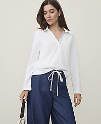A woman in a white collared shirt and wide-leg jeans stands against a plain, light-colored background. carousel Product Image 1