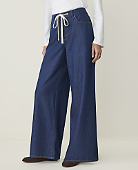 A person wearing wide-leg denim jeans with a white drawstring stands against a plain, light-colored background. carousel Product Image 2