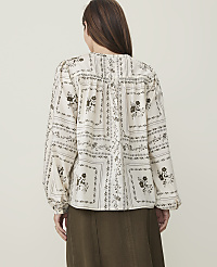 A woman in a patterned blouse and olive skirt stands against a plain, light background. carousel Product Image 2