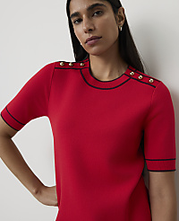 A woman in a red top with gold buttons stands against a plain white background. carousel Product Image 1