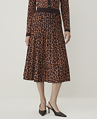 A person stands in a studio wearing a leopard print pleated skirt and matching cardigan, with a plain background. carousel Product Image 2